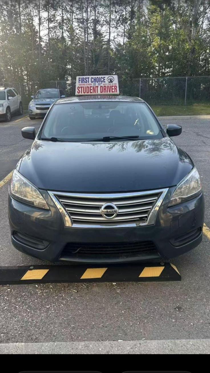 First-Choice Driving School's training vehicle with a Student Driver roof sign, parked in Calgary